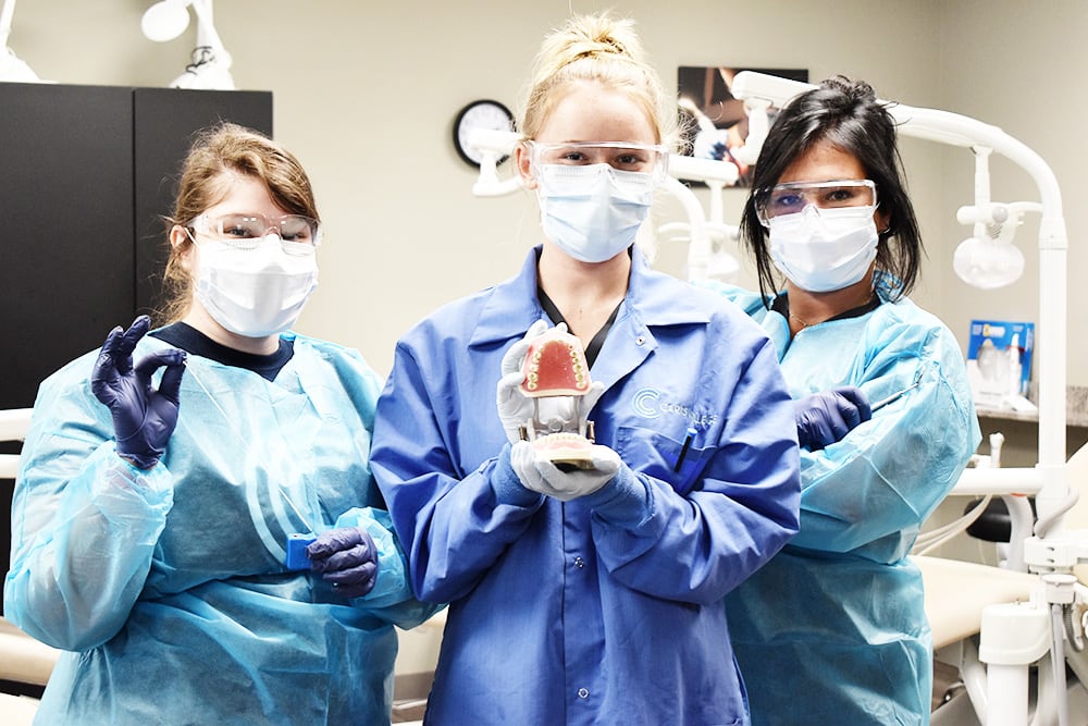 Dental Assisting students posing with fake teeth