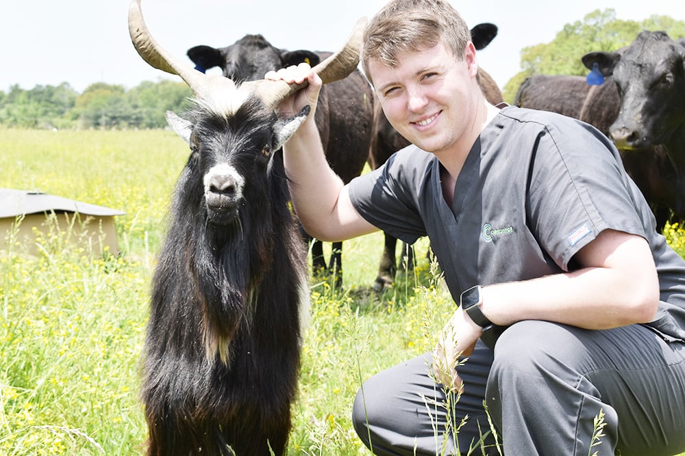 Veterinary Assisting student crouched with goat in field