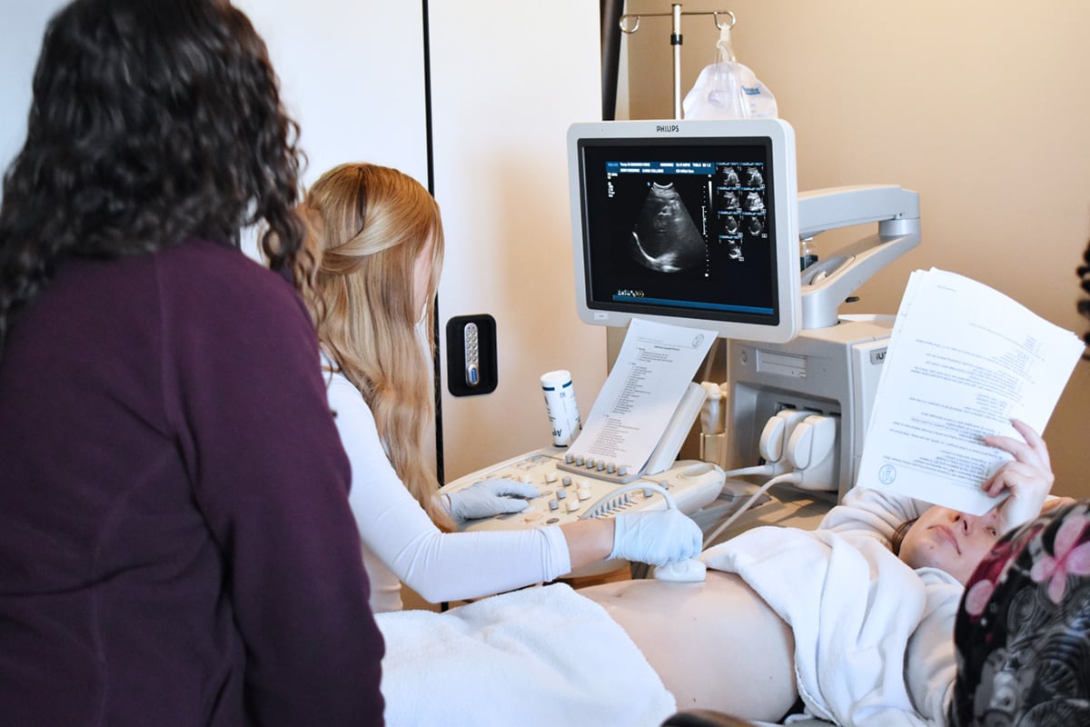 Caris College Sonography student performing exam as instructor looks on